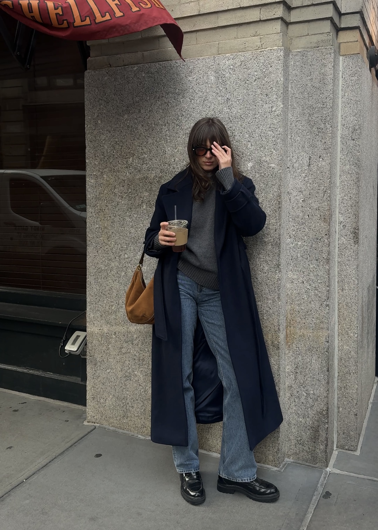 Kathryn Zahorak in new york wearing navy coat, grey sweater, jeans, and loafers