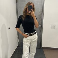 Nikki wears a black tee and white jeans.