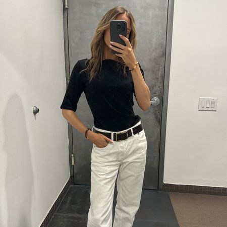 Nikki wears a black tee and white jeans.