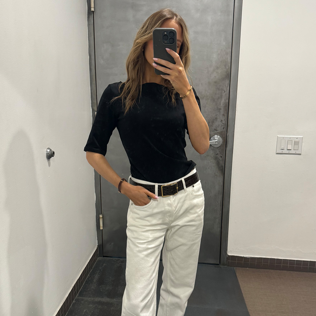 Nikki wears a black tee and white jeans.