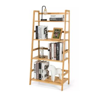 A wooden ladder shelf with four shelves, black and white books, and lamps on top of it