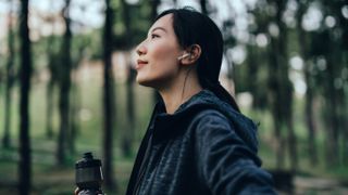 Woman running in forest wearing headphones