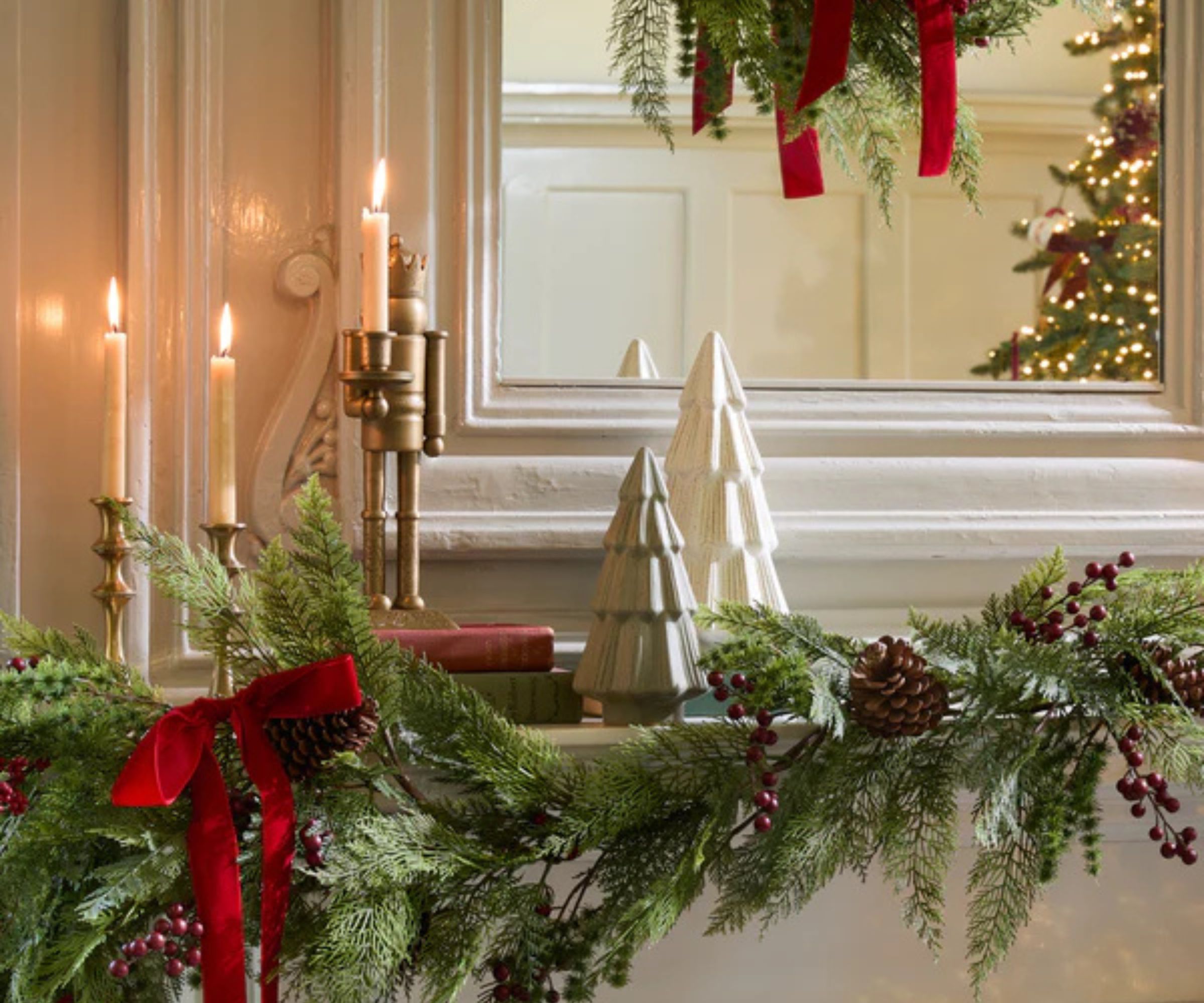 Mantelpiece with garland, candles, christmas tree ornaments, nutcracker and mirror