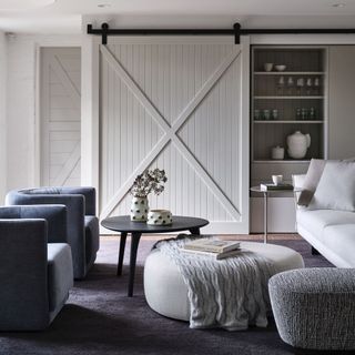 grey living room ideas, grey and white living room with sliding door, dark grey rug and armchairs, black coffee table, footstool, grey knitted throw