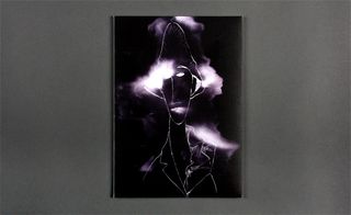 Front view of ﻿John Galliano's black, white and purple illustrated invitation pictured against a grey background