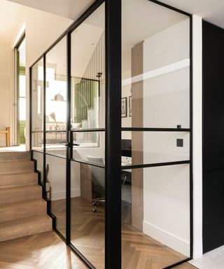 hallway with wooden flooring and office space with black framed glass walls