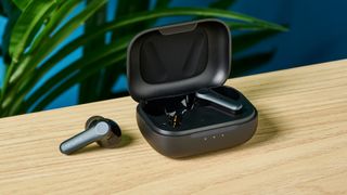 A photo of the EarFun Air Pro 4 earbuds out of their case on a wooden surface