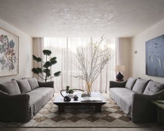 A living room with limewash walls, brown sofas and a thick rug