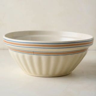 A fluted magnolia stone bowl with blue and red stripes around the rim