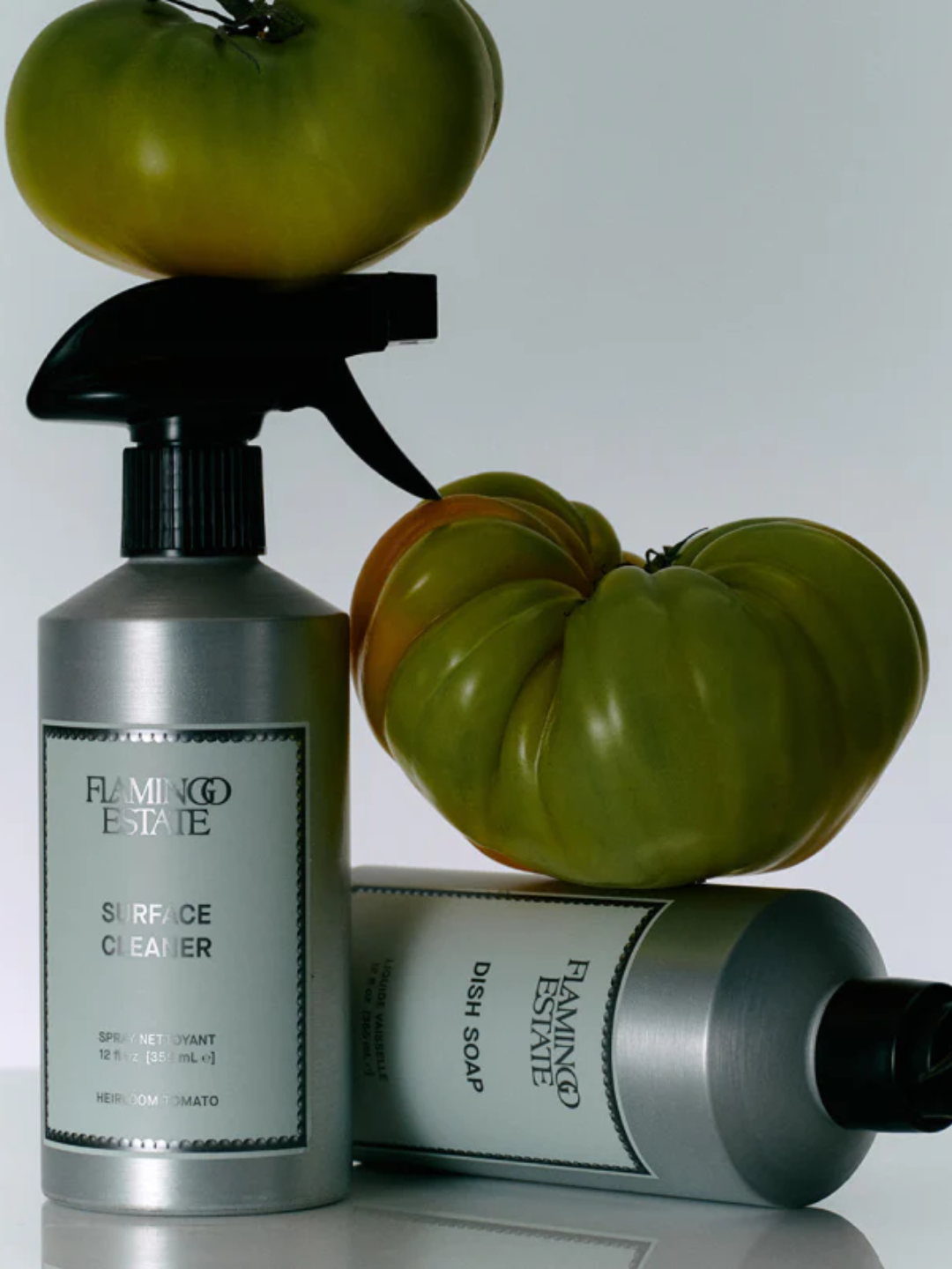A pair of steel bottles with dish soap and surface cleaner from Flamingo Estate with green heirloom tomatoes
