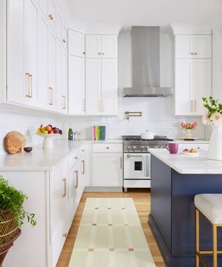 white kitchen kitchen with navy island and a patterned rug