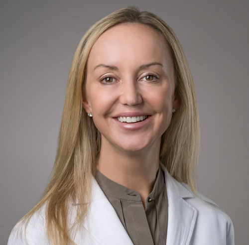 a blonde woman in a gray shirt and white lab coat