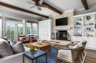 A neutral scheme with blue rug and exposed beams illustrating how to design a living room.