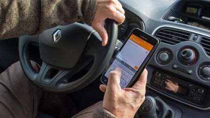 Motorist holding phone while driving