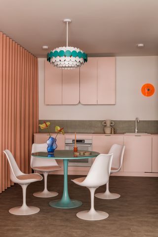 A dining room with turquoise table and peach cabinets