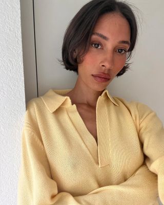 Wanita mengenakan sweter kuning pucat