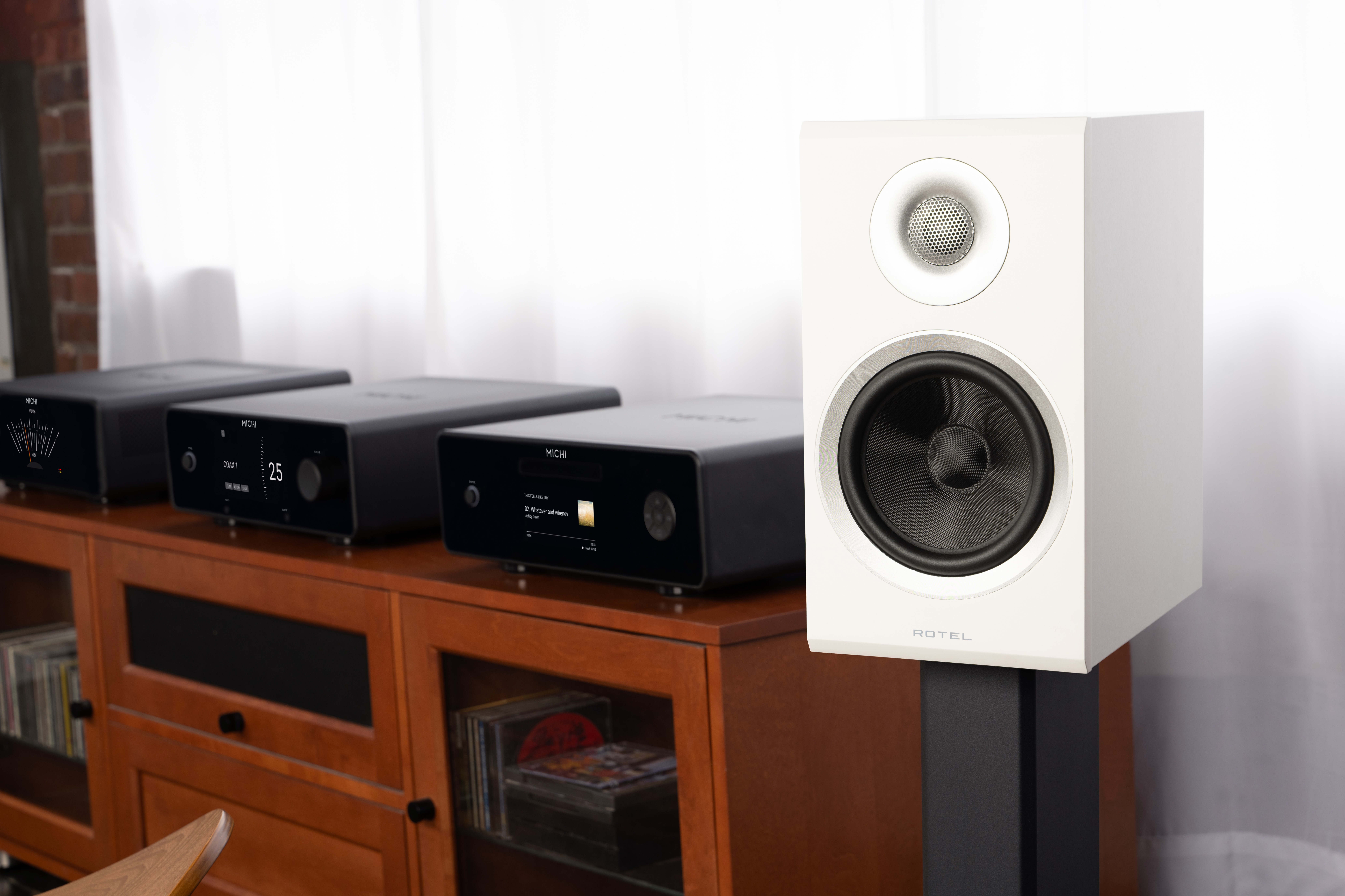 Rotel Amora 5 standmount speakers in white next to a hi-fi system