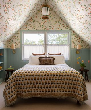 bedroom with sloped roof, patterned bedding, blue panelled walls and floral patterned ceiling