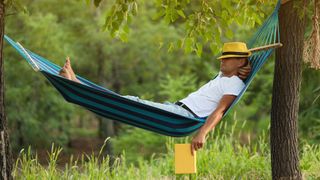 Man asleep in hammock with long grass beneath him