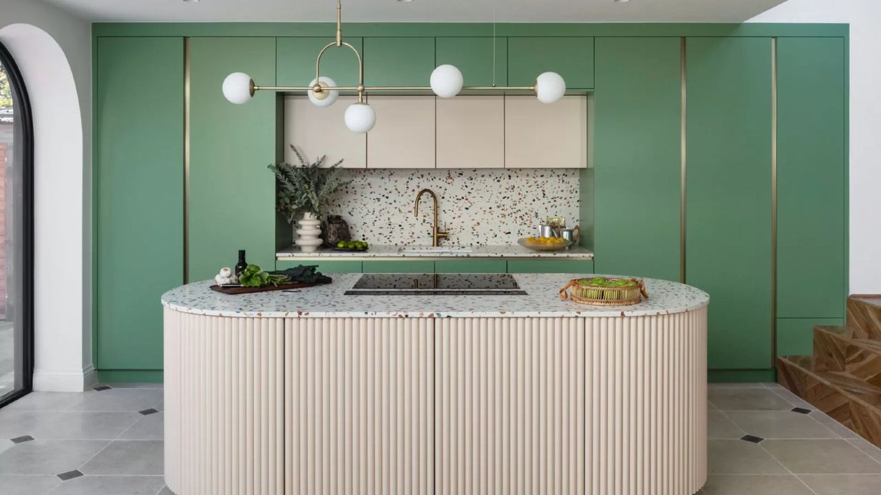 Round large kitchen island with fluted base, marble top, green painted cabinetry