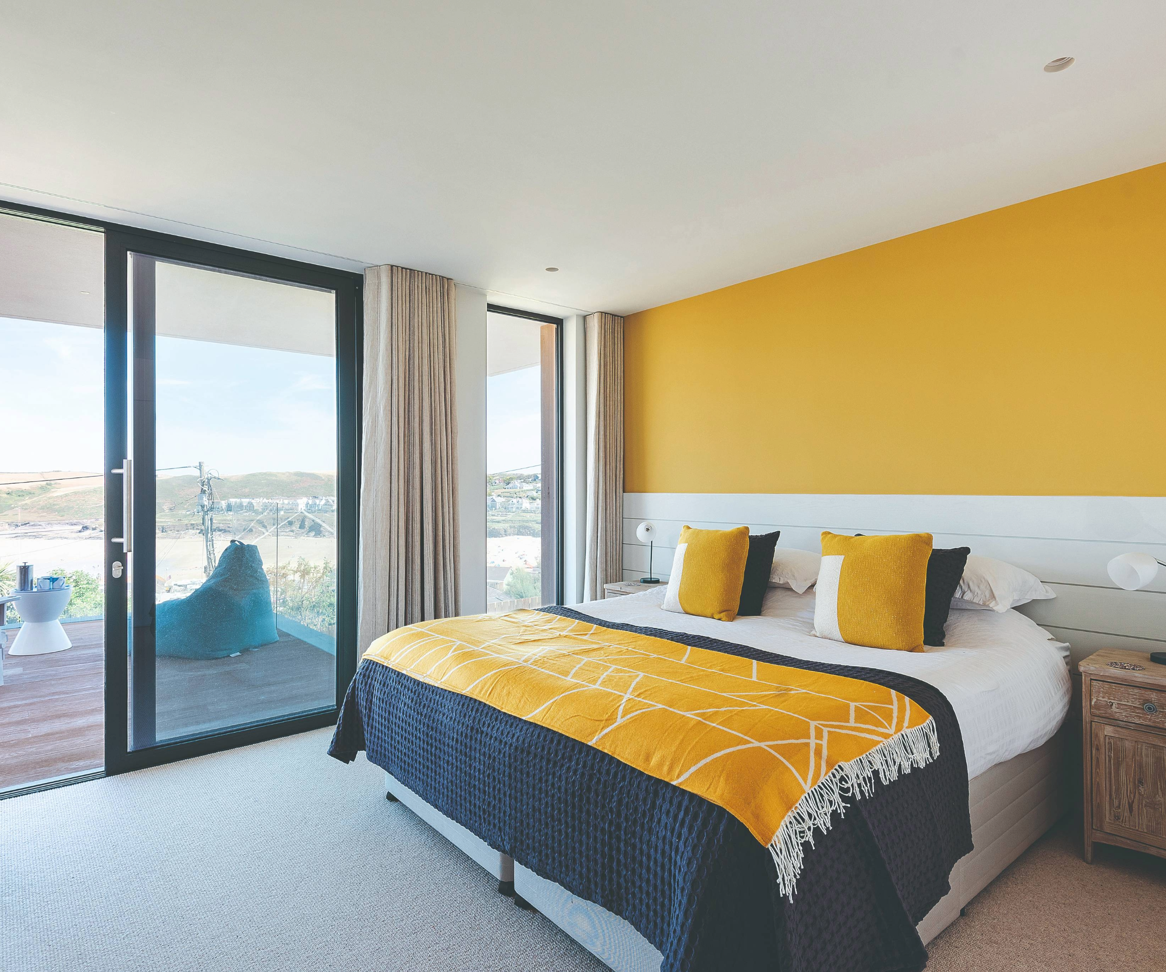 Yellow and navy bedroom with sliding doors that lead onto a balcony