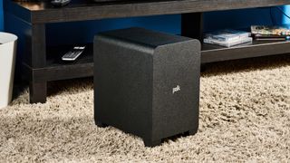 The Polk Audio Signa S4 subwoofer on the floor next to a TV stand