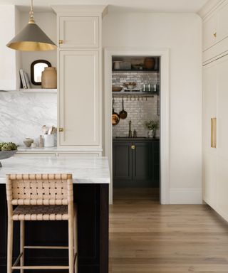 neutral kitchen with wood floor, warm white walls and cabinets, marble island