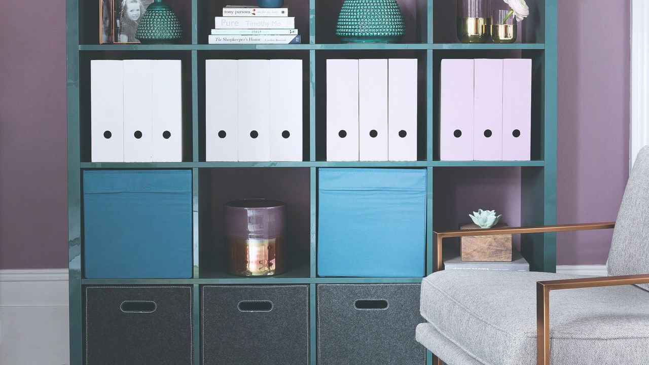 A purple-painted home office with a teal-coloured IKEA KALLAX storage unit