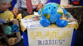 The new Celestial Buddies plush toy – Our Precious Planet – is on display at the New York Toy Fair. The company's older model, Earth, sits on a shelf to the left, along with other plush toy planets.