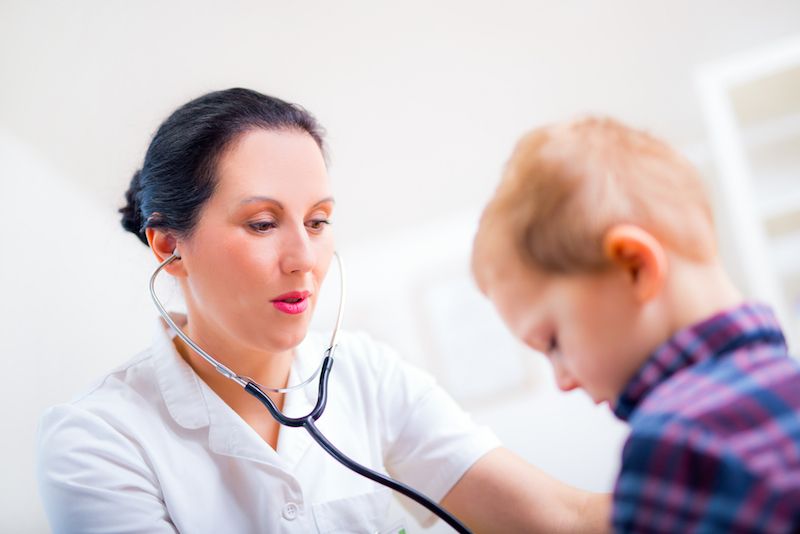 A doctor listens to a little boy&#039;s heart beat with her stethoscope