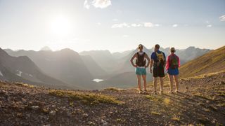 Three trail runners looking out from mountain top