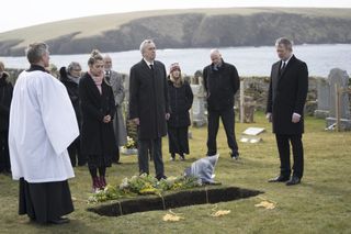 Cassie (Erin Armstrong), James (Benny Young) and Perez (Douglas Henshall) stand by an open grave looking desolate during the funeral of Perez's mother Mary