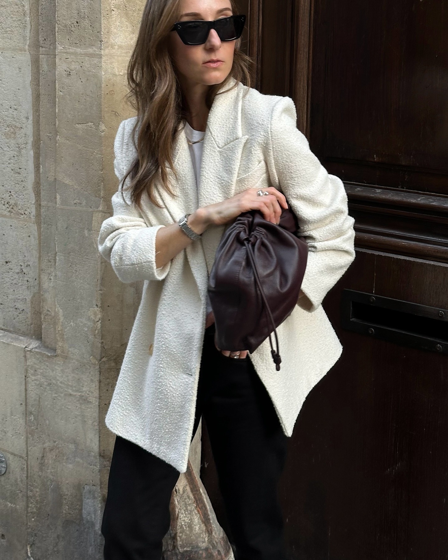 Influnecer @sarahrosepalm wears a cream boucle blazer with a burgundy clutch bag and black trousers.