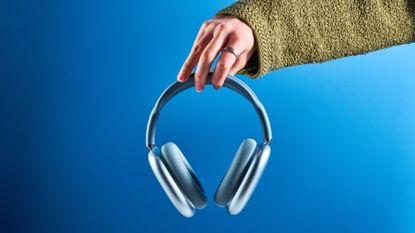 the apple airpods max 2 in blue photographed against a blue tom's guide background, showing the mesh headband, anodized aluminum ear cups, carry case, and controls