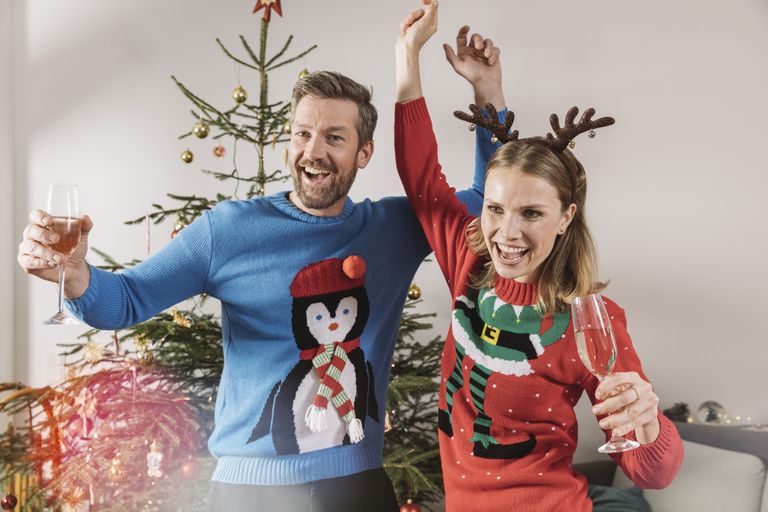 A man and a woman wearing traditional Christmas jumpers