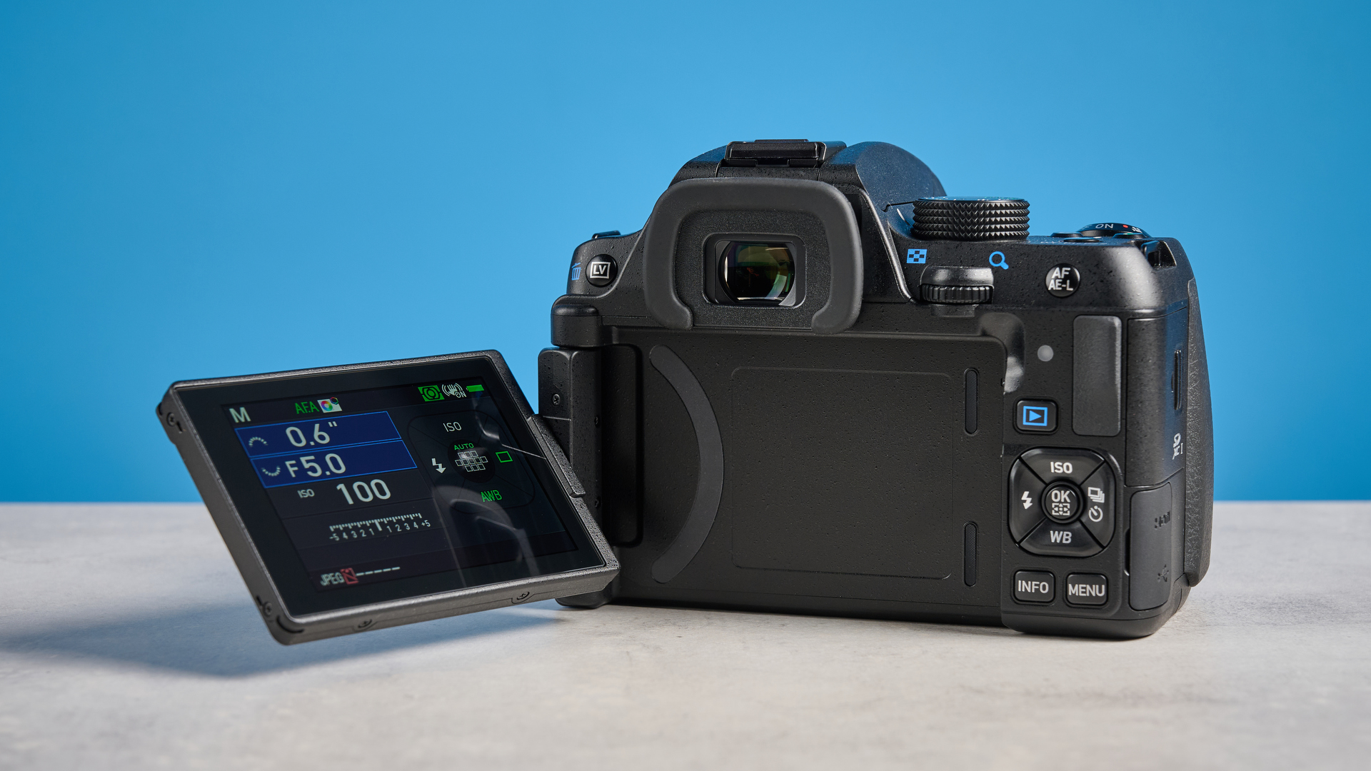 Pentax KF DSLR camera photographed on a blue background