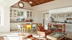 interior of a kitchen and living room in a light filled barn conversion including white kitchen and eclectic furniture