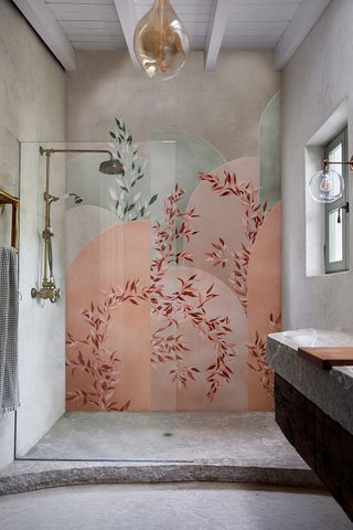 Shower design for a small bathroom featuring a pink and green floral wall design and curved stone floor.