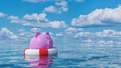 A piggybank floats in the water on top of a life preserver.