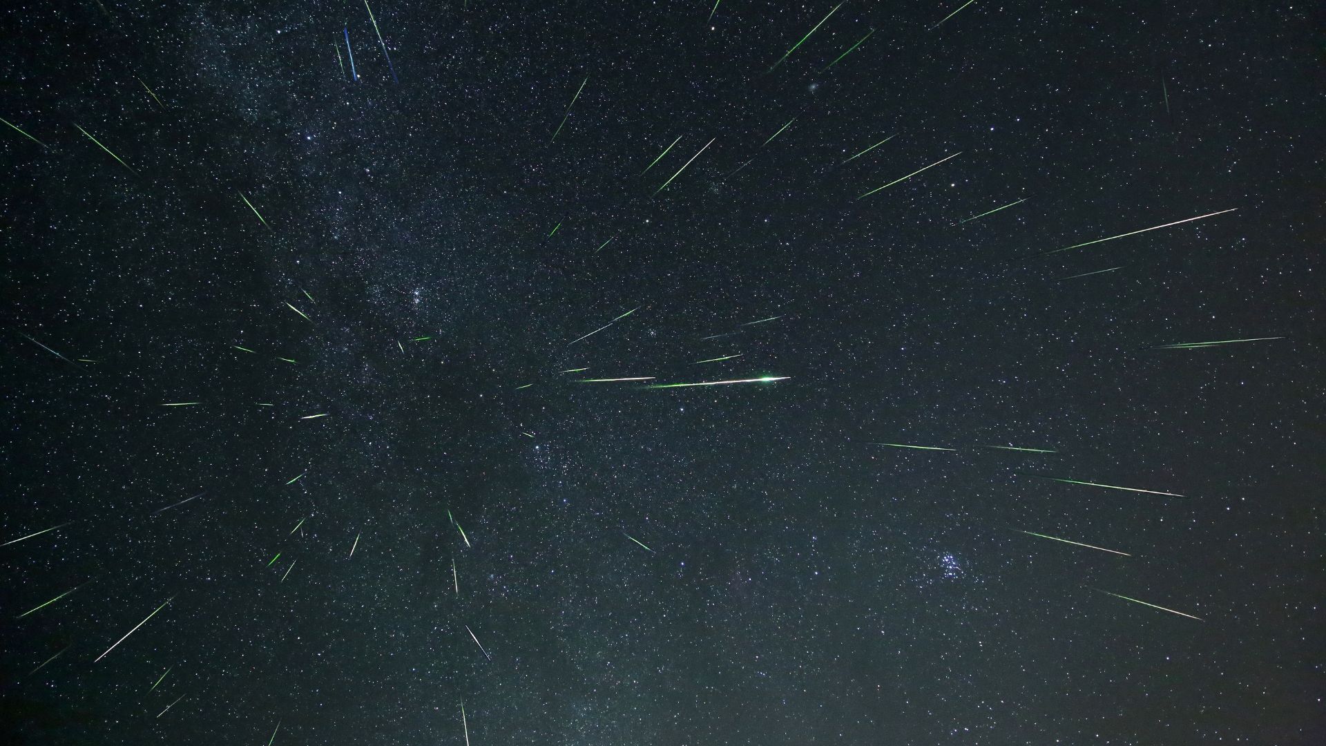 Dozens of meteors are photographed streaking towards the observed through a starry night sky.