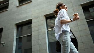 woman walking through city with coffee cup