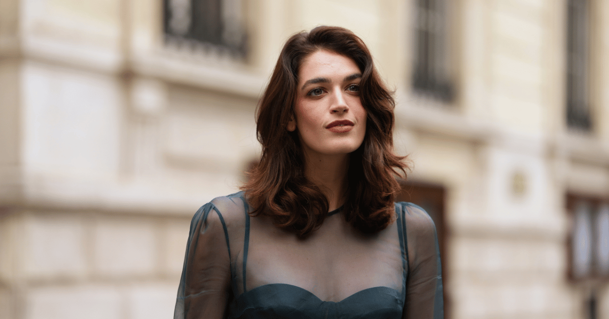 Makeup for hooded eyes Greta Ferro wears shoulder-length wavy dark brown hair with a side part, a sheer teal organza long-sleeve top layered over an opaque structured teal bustier with a sweetheart neckline, dramatic flared organza trumpet sleeves, a peplum-style waist composed of opaque and sheer organza panels, outside Zimmermann, during Paris Fashion Week - Womenswear Spring Summer 2026,