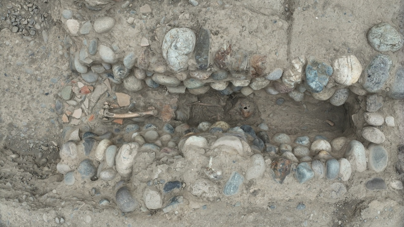 aerial image of a rock-lined channel in the earth with a human skeleton lying at the bottom