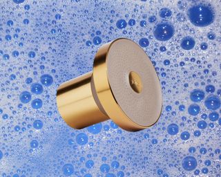 A gold Jolie shower head on a bubbly blue background