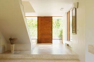 A minimalist modern hallway with stone flooring and huge windows giving a glimpse of the outside world