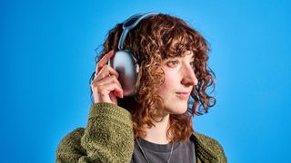 the apple airpods max 2 in blue photographed against a blue tom's guide background, showing the mesh headband, anodized aluminum ear cups, carry case, and controls
