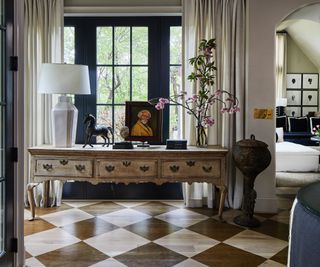 foyer with stained oak checkerboard floor, vintage console and black window frames