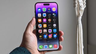 En mobiltelefon av typen iPhone 14 Pro Max holdt i en hånd