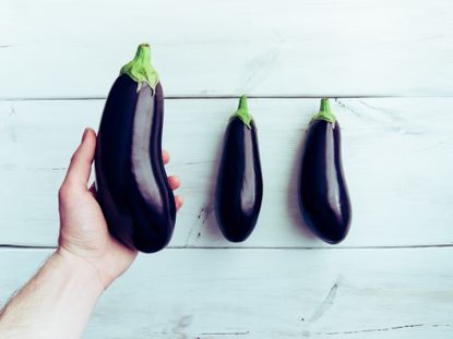 Cropped Hand Of Man Holding Eggplant Over Table