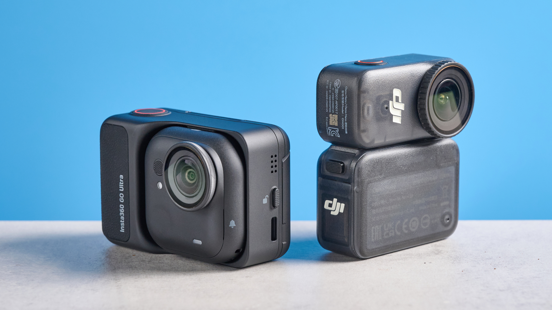 DJI Osmo Nano and Insta360 Go Ultra back to back on a gray surface against a blue background